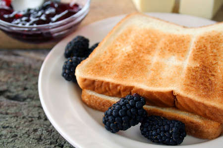 Fresh blackberries and blackberry jam with toast and butter. Used a shallow DOF on the berries and edge of toast.の写真素材