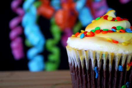 A single cupcake with sprinkles and colorful ribbons hanging in the background.  Copy space availabe.の写真素材