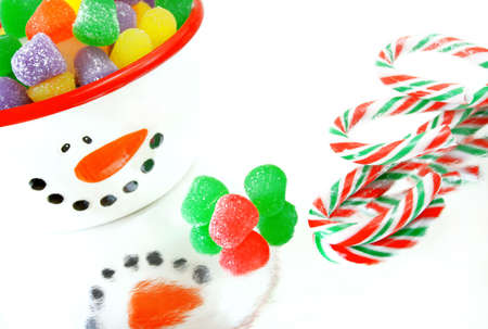 A high key image of Christmas candy.  Candy canes, spice gumdrops and a snowman candy dish.の写真素材