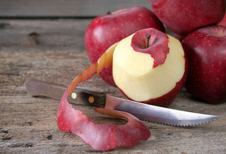 Peeling an apple with a knife on a rustic wood background.の写真素材
