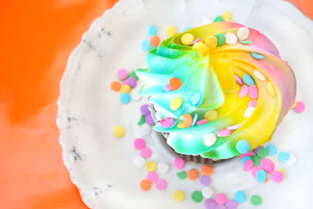 One cupcake with sprinkles shot on an orange background.の写真素材
