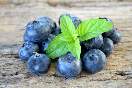 Grouping of blueberries with mint leaves and shot on a wood textured background for a rustic look.の写真素材