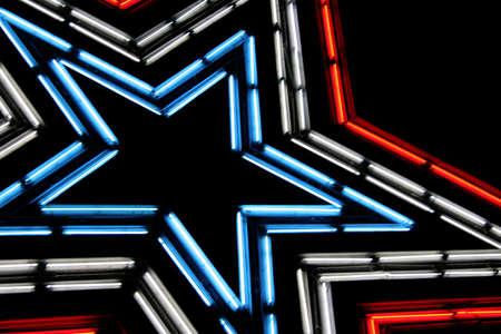 Large neon lit star with patriotic colors of red, white and blue.  Shot against the night sky.の写真素材