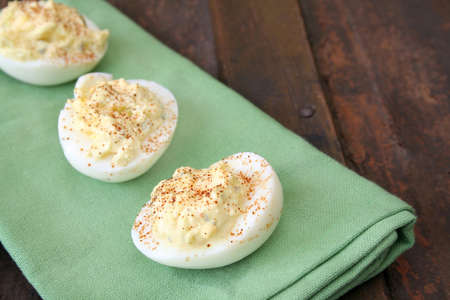 Deviled eggs laying on a green napkin on top of a wood table.  Room for your text.