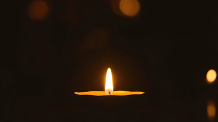 Golden diya glowing in darkness, symbolizing tradition and festive spirit in Indian culture.の素材