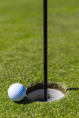Close up of a golf ball on the edge of a hole の写真素材