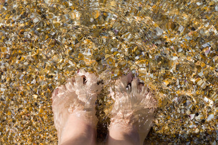 Women feet on the background of sand and seashells. Summer vacation concept. Vacation at the beach