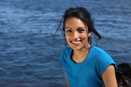 Dazzling smile young woman in t-shirt by the seaの写真素材
