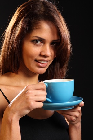 Young woman with a refreshing cup of tea on black backgroundの写真素材