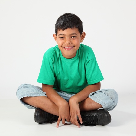 Smiling school boy sitting cross legged on floorの写真素材