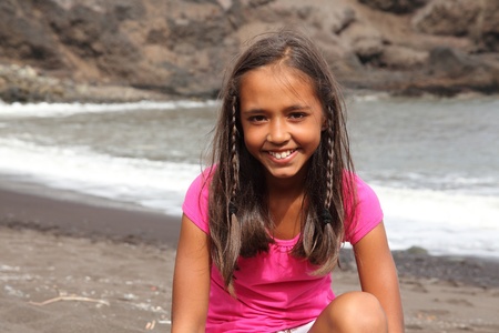 Cute smile from young school girl sitting on the beachの写真素材