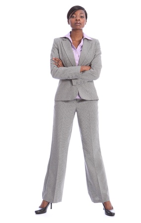 Serious and confident young african american business woman, full length shot standing in grey suit with arms folded.の写真素材