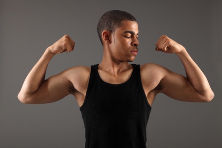 Bicep muscles on fit body of a handsome young african american man showing off his physique wearing...