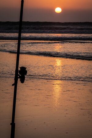 Silhouette of fishing rod at sunsetの写真素材