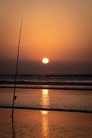 Silhouette of fishing rod at sunsetの写真素材