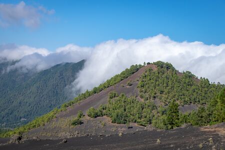 Clouds rolling over the volcanic blast crater ridge at Llanos del Jable, La Palma, Canary Islands,...