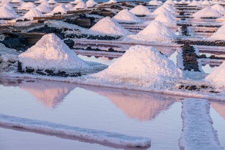 Rows of salt piles and different colours of water basins during the evaporation and salt collection processの写真素材