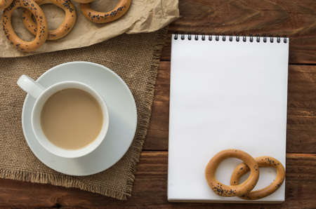White notepad with bagels and coffee on the wooden table.の写真素材