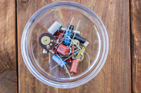 The radio parts in the glassy saucer on the wooden table. View from above.