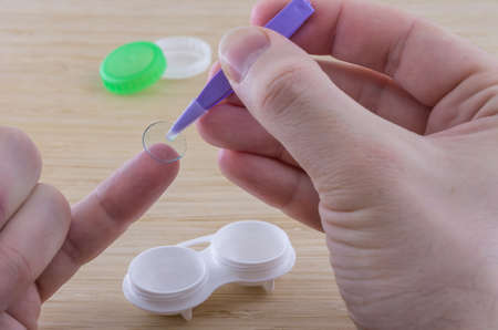 Procedure of putting the lens to the fingertip with tweezers. Blurred vision. Angle view.