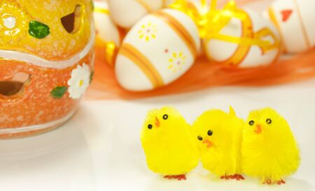 Yellow toy chicks and decorated eggsの写真素材