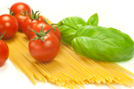 red tomatoes and green leaves of basil with spaghettiの写真素材