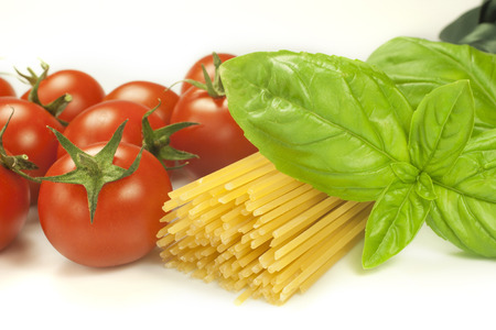 red tomatoes and green leaves of basil with spaghettiの写真素材