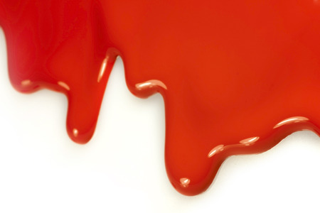 Red paint dripping from a white wallの写真素材