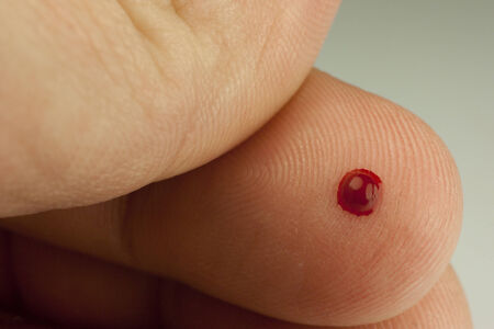 small drop of blood on the tip of a fingerの写真素材