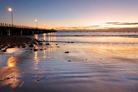 Morning light reflections from the jetty on the wet sandの写真素材