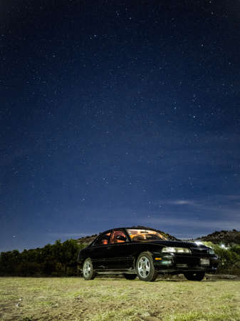 Photograph of a car parked on the side of the road, with the stars in the background, taken in Oaxaca Mexicoの写真素材