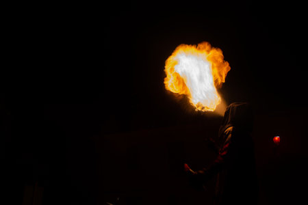 shadow of unrecognizable masked man spitting fire from his mouth in the middle of the nightの写真素材
