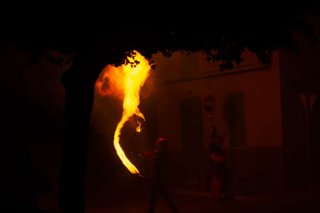 masked man amid smoke and sparks shooting fire from his mouth