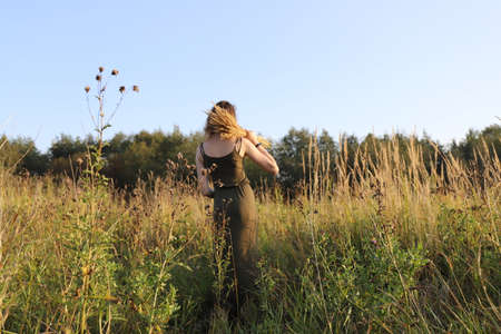 summer in the russian village - young girl walking in the field on the countrysideの写真素材