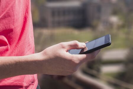 T-shirt holds the phone. Smartphone, touchscreen, get a message, background mode, men's hands.