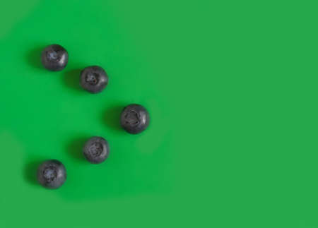 Blueberry as a pointer arrow on a bright green background. High quality photo