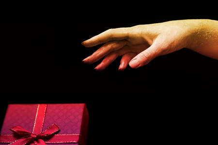A beautiful female yellow and red hand wants to take a color present on a black isolated background, banner concept artの写真素材