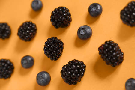 Blackberries and blueberries on a marigold background. High quality photoの写真素材