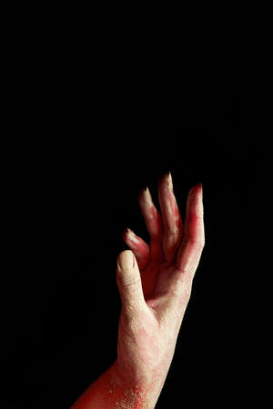 A beautiful horror red female hand stretches your product on a black isolated background, concept artの写真素材