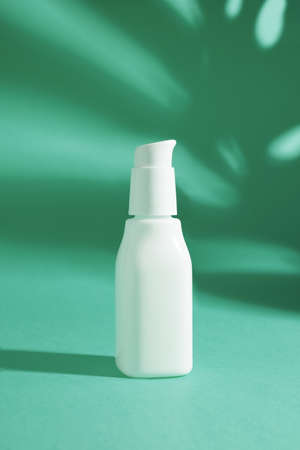 White ceramic opaque bottle on a bright green background without labels on natural background with shadowsの写真素材