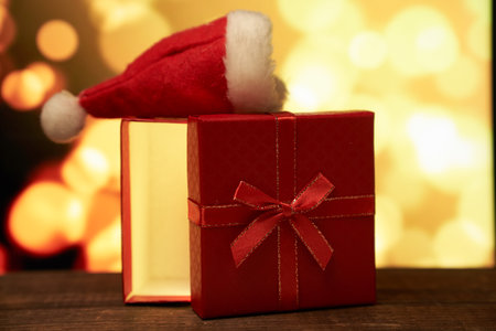 New years red gift with a bow on a brown wooden table on a gold bokehの写真素材