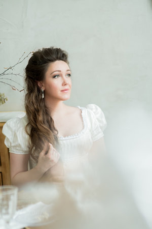 Vintage portrait of a beautiful woman with long hair in a white dress of 19th century. She looks away. Historical reconstructionの写真素材