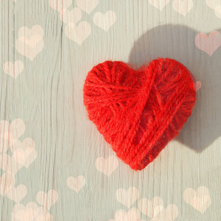 Red heart made of wool threads on a light wooden background. High quality photo