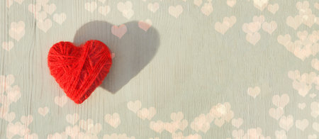 Red heart made of wool threads on a light wooden background. High quality bannerの写真素材
