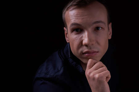 Close up portrait of a beautiful confident young man on a black isolated background in a Studio with copy space, he looks at the cameraの写真素材