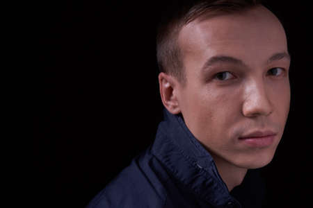 Close up portrait of a beautiful confident young man on a black isolated background in a Studio with copy space, he looks at the cameraの写真素材