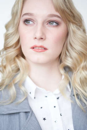 Portrait of a beautiful blonde business woman on a white background in a gray vest and blouse looking awayの写真素材