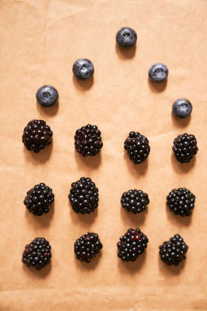 Five blueberries and twelve blackberries on a beige background, laid out in the form of a house. High quality photoの写真素材