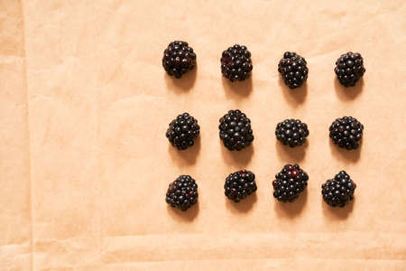 Twelve blackberries on a beige craft paper background. Berries laid out in the form of a rectangle. Horizontal card with copy space. Healthy, delicious, natural vegetarian background.の写真素材