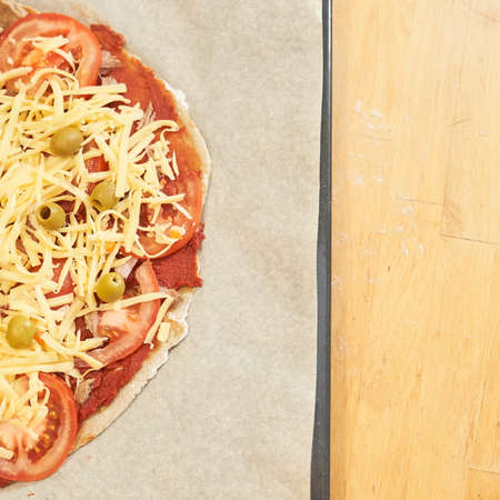 Pizza with beef on baking paper prepared for baking. Healthy gluten-free pizza on wooden table. Gluten-free cooking class. Photo with copy space.の写真素材